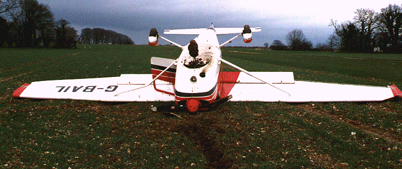 G-BAIL inverted near a grass strip which is visible to the right